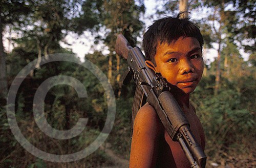 Photograph of a boy in Cambodia with an AK-47 gun