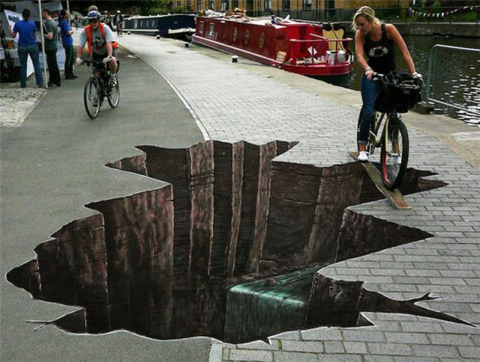 Photo of street art sink hole with bicylist