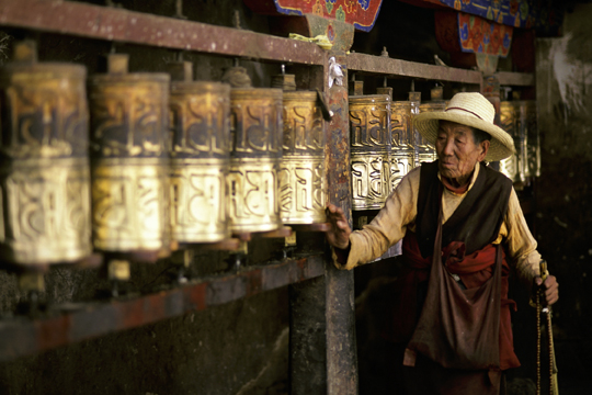 Tibetan pilgrim spinning prayer wheels in Lhasa, Tibet